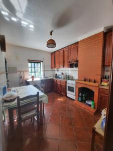 eine Küche mit Holzschränken, einem Tisch und einem Kamin in der Unterkunft Casa Penafalcão in Castelo Branco