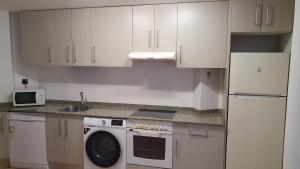 Una cocina con gabinetes blancos y lavadora. en La Yecla Teruel, en Teruel