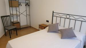 1 cama blanca con 2 almohadas y 1 silla en La Yecla Teruel, en Teruel