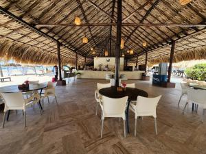 una zona de comedor con mesas y sillas y un techo de paja. en Sunsol Punta Blanca en San Pedro de Coche