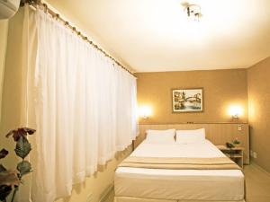 マリンガにあるGOLDMEN HOTEL MARINGÁのベッドルーム(白いカーテン付きの大型ベッド1台付)
