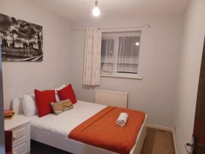 Un dormitorio con una cama con almohadas rojas y una ventana en Fieldfare Green-Huku Kwetu Luton & Dunstable Spacious 4 Bedroom Detached House - Free Parking- Field View-Affordable Group Accommodation - Business Travellers, en Luton