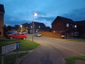 a red car parked on the side of a street at Fieldfare Green-Huku Kwetu Luton & Dunstable Spacious 4 Bedroom Detached House in Luton