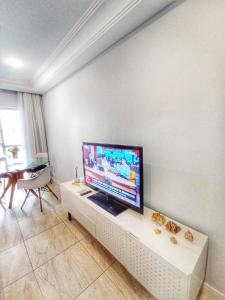 a living room with a flat screen tv on a white wall at Ap Brisa do Mar Praia da Costa in Vila Velha