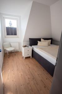 a bedroom with a bed and a chair and a window at NB Katharinenviertel Zwei Zimmer Wohnung in Neubrandenburg