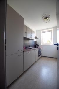an empty kitchen with white cabinets and a window at NB Katharinenviertel Zwei Zimmer Wohnung in Neubrandenburg