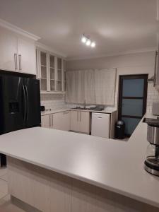 a kitchen with white cabinets and a black refrigerator at Desert Escape J8 in Swakopmund