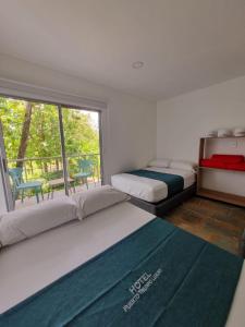 1 dormitorio con 2 camas y ventana grande en Hotel Puerto Triunfo, en Doradal