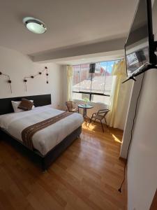 Cusco Rooms في كوسكو: غرفة نوم بسرير وطاولة وتلفزيون