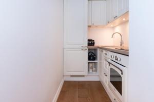 a white kitchen with white cabinets and a sink at Sunny Terrace Flat with AC Free WiFi Self Check In in Pärnu