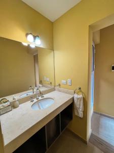 baño con lavabo y espejo grande en Ayllupelli en Villa Berna