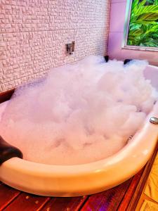eine Badewanne, gefüllt mit einer Wolke wie Substanz in der Unterkunft Prana Guest House in Praia do Rosa