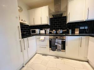 a kitchen with white cabinets and a stove top oven at Gytes Lane, Manchester with FREE Parking and FREE Wi-Fi in Manchester