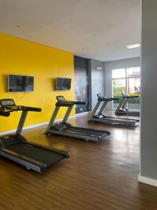 a row of treadmills in a gym with a yellow wall at Lindo apartamento no shopping in Águas Claras