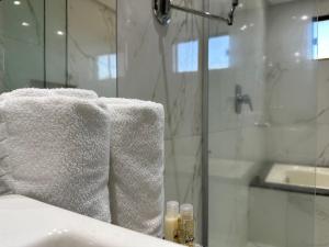 a bathroom with a shower and white towels on a tub at Atrium Confort Hotels in Parauapebas