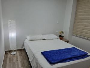 een slaapkamer met een bed met een blauwe deken erop bij Apartahotel AMARU in San Gil