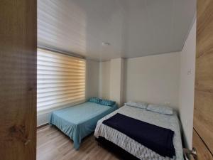 een kleine slaapkamer met een bed en een raam bij Apartahotel AMARU in San Gil