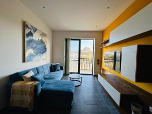 uma sala de estar com um sofá azul e uma grande janela em Del Mar Apartment! em Żebbuġ