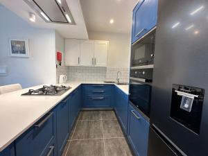 uma cozinha com armários azuis e um frigorífico preto em Del Mar Apartment! em Żebbuġ