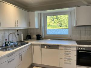 eine weiße Küche mit einem Waschbecken und einem Fenster in der Unterkunft Ferienwohnung Heide in Freudenstadt