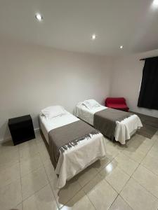 a room with two beds and a red chair at Departamento Centro Jujuy 2 in San Salvador de Jujuy