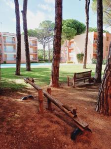 a fallen log in a park with a bench and trees at Apartamento con piscina cerca de la playa in Pals