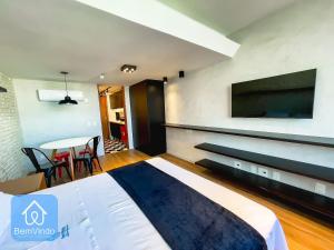a bedroom with a bed and a tv and a table at Apartamento completo com píer e acesso ao mar in Salvador