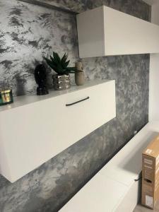 a kitchen with white cabinets and a plant on a wall at Apartament ultra central in Craiova