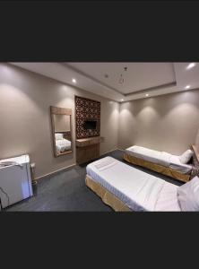 a bedroom with two beds and a mirror at فندق قافلة الحجاز in Makkah