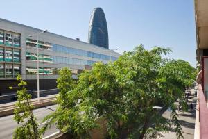ein Baum vor einem Gebäude mit einem Wolkenkratzer in der Unterkunft Glorias:Sagrada Familia 15 minutos - Playa 20 minutos in Barcelona
