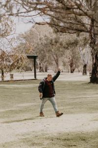 Um homem está a lançar um papagaio num parque. em The Paddock at Ulupna 