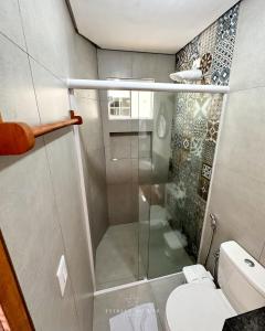 a bathroom with a toilet and a glass shower at Pousada Estrela do Mar in Barra Grande