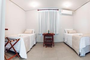 um quarto com duas camas e uma mesa e uma janela em Pousada Estrela do Mar em Barra Grande