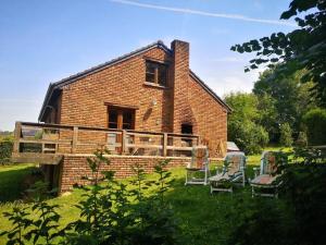 een oud bakstenen huis met twee stoelen in de tuin bij Maison familiale avec jacuzzi et jardin au calme in Sprimont