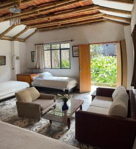 a bedroom with two beds and a living room with a couch at Casa Carmelita Hotel Boutique Pitalito in Pitalito