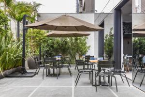 a patio with tables and chairs and an umbrella at Helbor Stay Batel in Curitiba