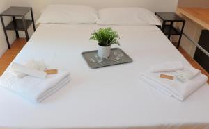 ein weißes Bett mit einem Tablett mit einer Pflanze darauf in der Unterkunft La Ca' Fiera Affittaly Apartments in Bologna