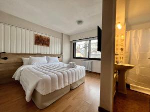 - une chambre avec un grand lit blanc et une fenêtre dans l'établissement El Residencial Bariloche, à San Carlos de Bariloche
