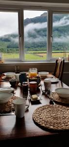 a wooden table with plates and dishes on it with two windows at Clachan Farmhouse B & B in Ullapool