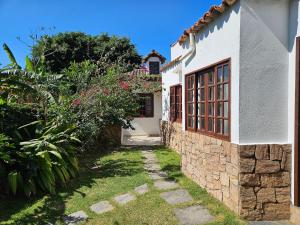 a house with a stone wall and a yard at Suite Dupla em Búzios in Búzios