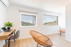 a white room with a desk and chairs and two windows at Loriga View Apartments in Loriga