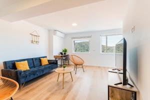 a living room with a blue couch and a tv at Loriga View Apartments in Loriga