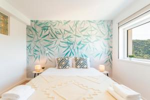 una camera da letto con un letto e un murale tropicale sul muro di Loriga View Apartments a Loriga