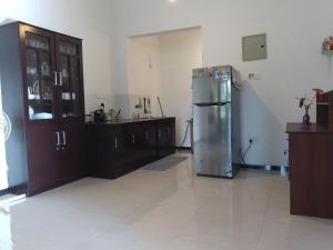 a kitchen with a stainless steel refrigerator and wooden cabinets at Sea & Greens Apartments in Unawatuna