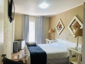 a hotel room with a bed and a window at Hotel Solar da Montanha in Campos do Jordão