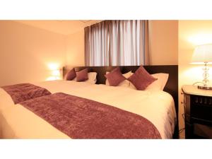 Centurion Hotel Villa Suite Fukui Ekimae - Vacation STAY 34532v في فوكوي: غرفة نوم مع سرير أبيض كبير مع وسائد أرجوانية