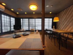 een grote kamer met een tafel, stoelen en ramen bij Kawamura Building 3F - Vacation STAY 47042v in Kusatsu
