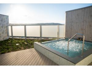 een hot tub op een terras met uitzicht op het water bij Hotel Grand View Takasaki - Vacation STAY 55422v in Takasaki