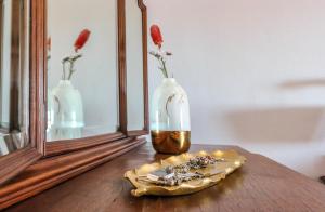 una mesa con espejo y un jarrón con flores en Fonte da Rosa Guest House, en Belmonte