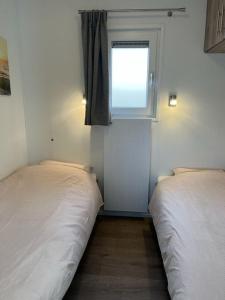 two beds in a small room with a window at Moderne chalet met airco in Blankenberge in Blankenberge